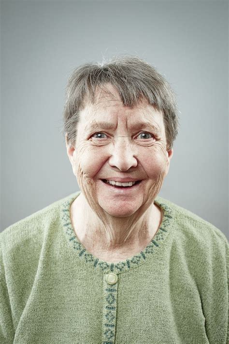 an older woman with gray hair and green shirt smiling at the camera ...