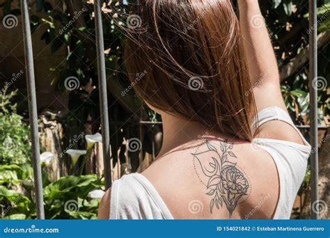 A Young Red-haired Tourist with an Arum-lily Tattoo on Her Back Looks ...