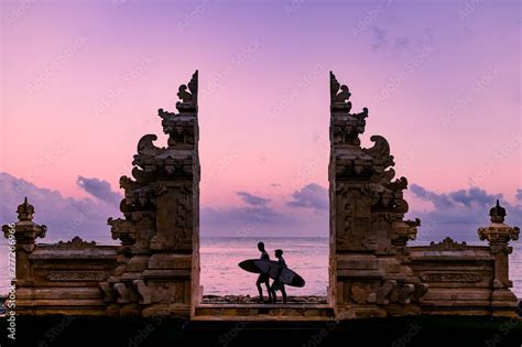 Surfers Walk Past Gate in Bali During Sunrise Stock Photo | Adobe Stock