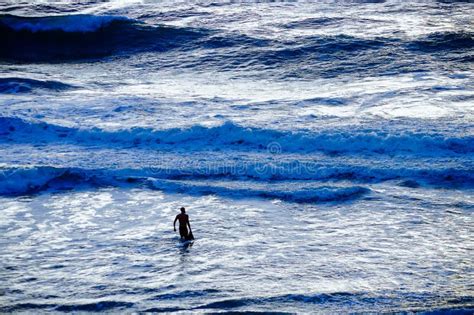 Surfer Striding Towards Big Waves in Turbulent Sea at Dusk Stock Photo ...