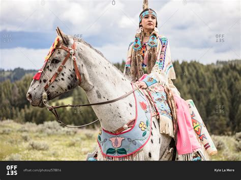 Native American young woman dressed in regalia riding a spotted horse ...