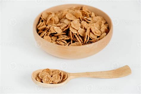 Crispy healthy dry cereal flakes in a wooden bowl with wooden spoon on ...