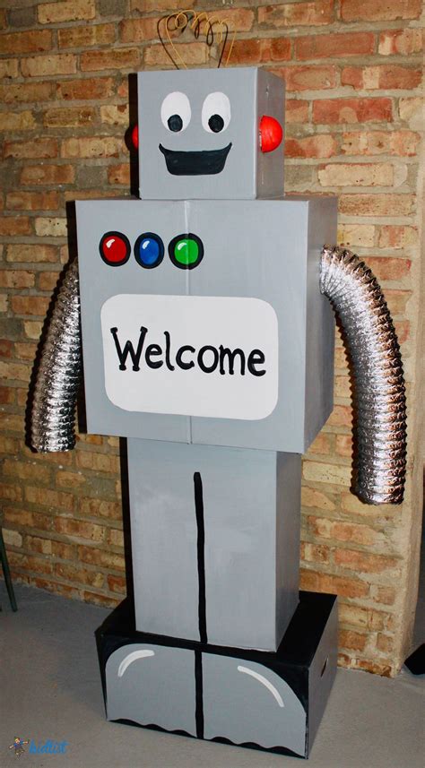 a welcome sign is placed on top of a small robot statue in front of a ...