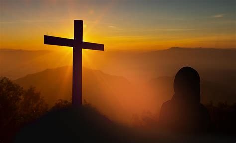 Silhouette of woman holding a bible praying In front of the cross on ...