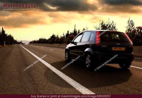 Car driving by highway at sunset. Stock Photo MXI20257