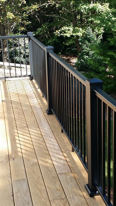 a wooden deck with metal railings and trees in the background