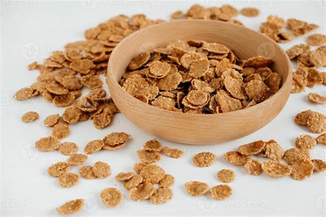 Crispy healthy dry cereal flakes in a wooden bowl on white background ...