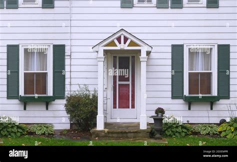 Modest white clapboard house with green shutters around windows Stock ...