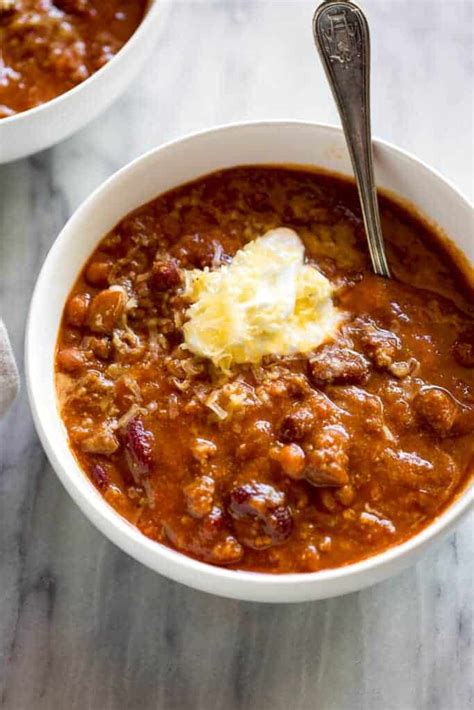 Overhead view of a white bowl full of chili with sour cream and ...