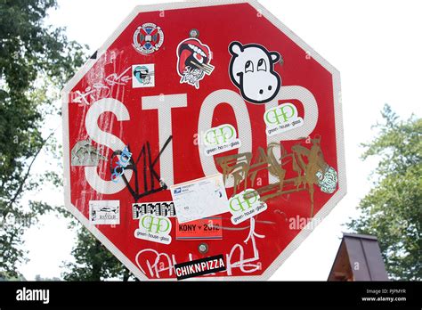 Stop sign covered in stickers and graffiti Stock Photo - Alamy