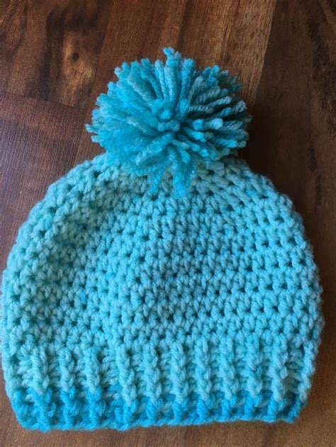 a crocheted hat with a blue pom - pom