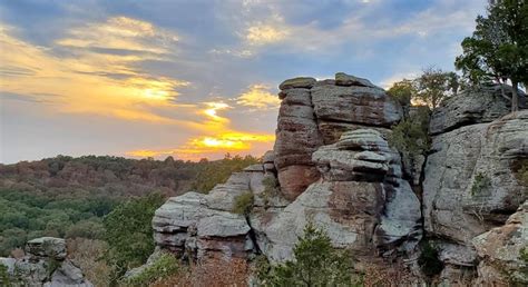 the sun is setting over some rocks in the mountains near trees and ...