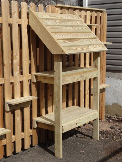 a wooden bench and shelf in front of a fenced off area with wood slats