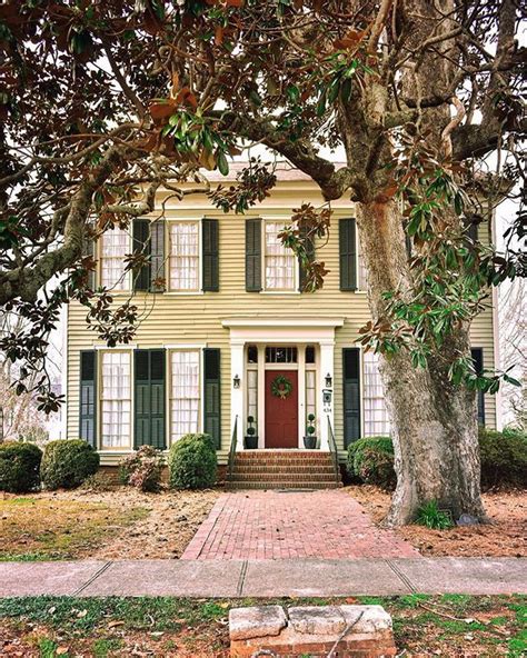 a yellow house with green shutters and a red door