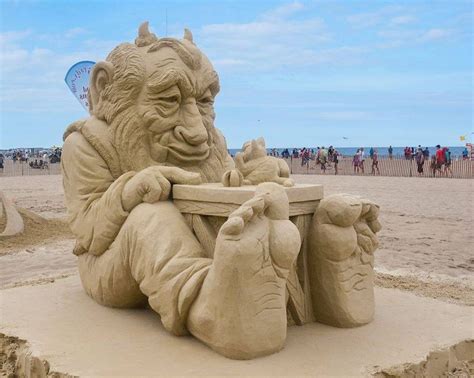 a sand sculpture of a man sitting at a table on the beach