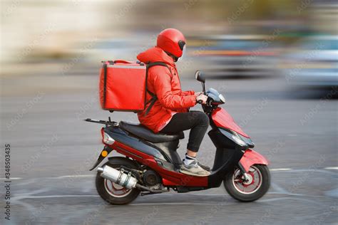 Food delivery moto scooter driver with red backpack behind back is on ...