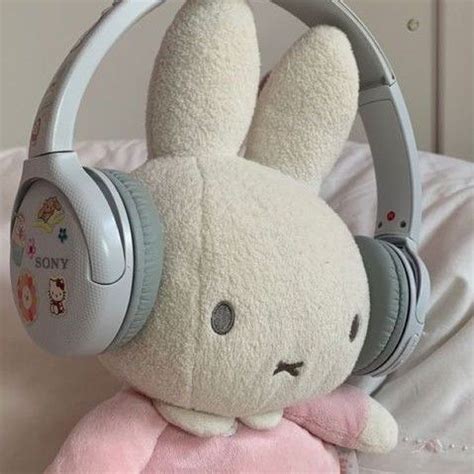 a stuffed animal with headphones on it's ears sitting on top of a bed