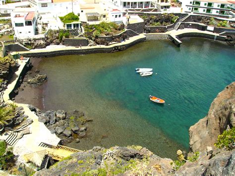 two boats are in the clear blue water near some houses and cliffs ...