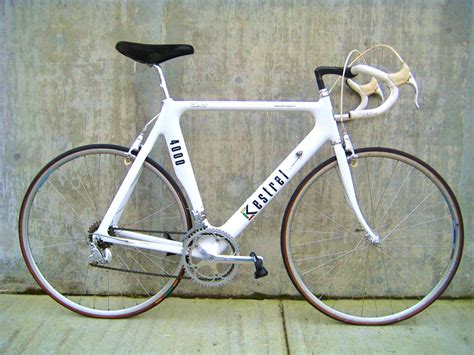 a white bike parked next to a cement wall