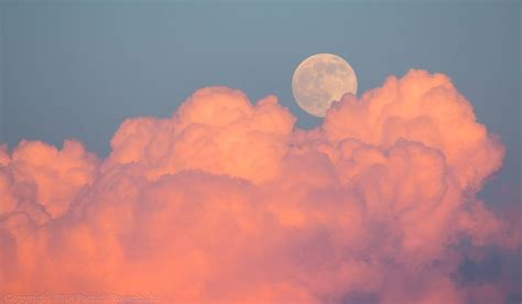 a full moon is seen through the clouds