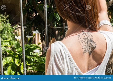 A Young Red-haired Tourist with an Arum-lily Tattoo on Her Back Looks ...