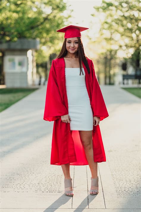 a woman in a graduation gown and cap is standing on the sidewalk with ...