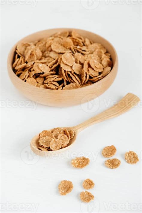 Crispy healthy dry cereal flakes in a wooden bowl with wooden spoon on ...