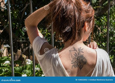 A Young Red-haired Tourist with an Arum-lily Tattoo on Her Back Looks ...