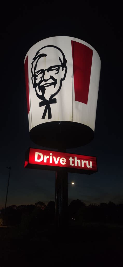 KFC Neon Sign with Red and White Flag at Night