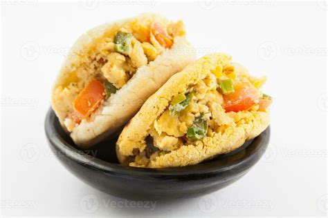 Arepas filled with scrambled eggs served in a black ceramic dish on ...