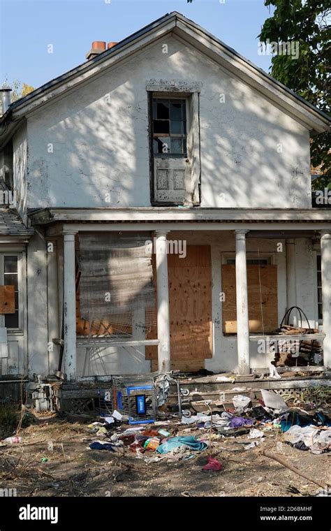 An abandoned boarded up house with trash all around Stock Photo - Alamy