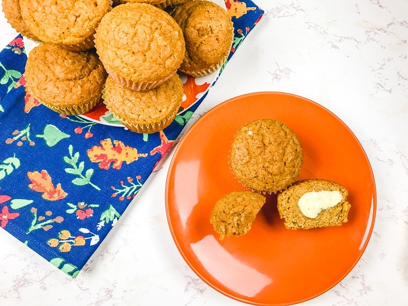 A pumpkin cornbread muffin cut in half and slathered with butter.