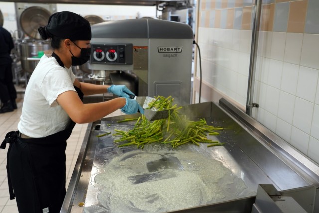 Spc. Nhien Nguyen, Field Feeding Platoon, 35th Combat Sustainment Support Battalion, 10th Support Group, prepares sautéed asparagus as part of the U.S. Army's main course during the Japan-wide Joint Culinary Competition, held Oct. 20-21, Camp...