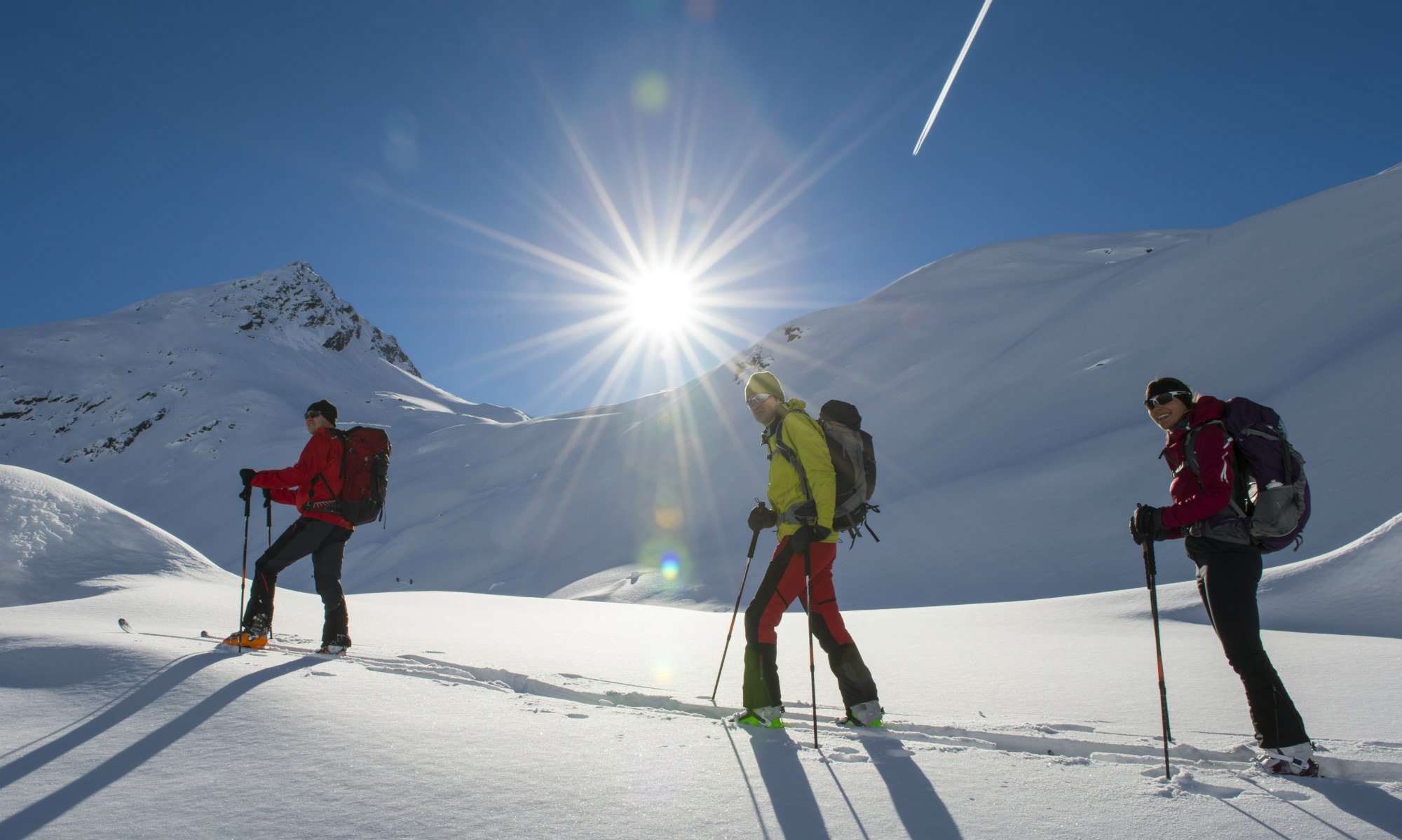 3 persone in un tour sciistico attraverso il paesaggio montano innevato.