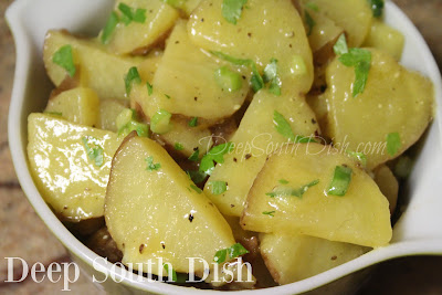 A cold potato salad, made with red skin potatoes, toss with white wine, and dressed with a lemon and mustard vinaigrette and tossed with green onions and herbs.