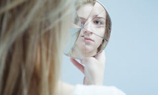 Image of woman with mental disorder holding broken mirror