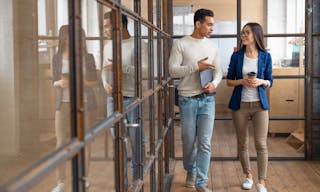 Young asian businesswoman discussing with her colleague in the office building. Two business people walking and talking over wor