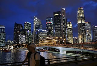 People walk past the skyline of the central business district in Singapore