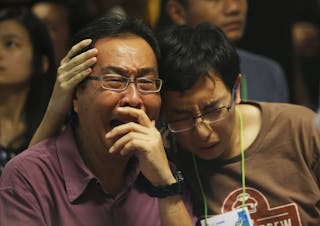 Family members of passengers onboard missing AirAsia flight QZ8501 cry at a waiting area in Juanda International Airport