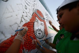 Saudi boys paint a mural depicting Saudi Arabia's Deputy Crown Prince Mohammed bin Salman during an activity for national drawin