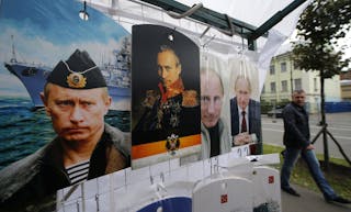 A man walks past cutting boards, that have been painted with images of Russia's President Vladimir Putin, at a street store in t