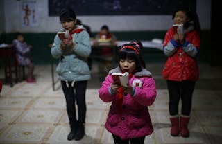 Students read a lecture from Mao Zedong's "Little Red Book" at the Democracy Elementary and Middle School in Sitong town, Henan 