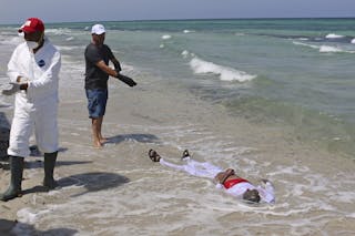 Libyan Red Crescent workers check the body of a dead migrant that was recovered by the Libyan coastguard after a boat sank off t