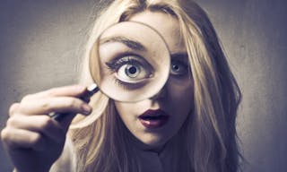 Young woman looking through a magnifying glass — Photo by olly18