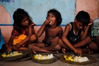 Children eat their lunch in a free meal centre at the cyclone-hit Gopalpur village