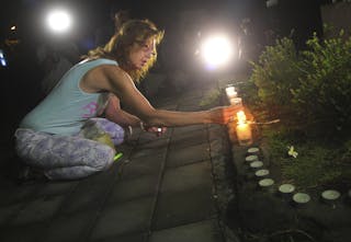 A woman lights a candle before praying in front of Kerobokan prison, before the transfer of the two Australian death row prisone