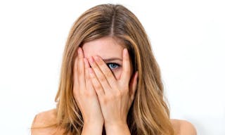 woman hiding face laughing timid on white background