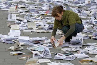 A woman arranges books on the pavement during an event marking the World Book and Copyright Day in downtown Bucharest