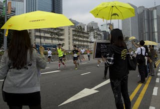 Occupy supporters hold yellow umbrellas as they cheer on participants in the Hong Kong Marathon