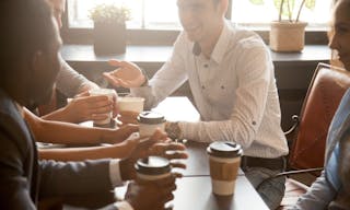 Multi ethnic group of happy friends drinking coffee in paper cups together in cozy cafe, diverse multiracial african and caucasi